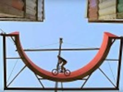 Un  biker  canadiense hace una demostración en una rampa vertical suspendida sobre dos pilas de contenedores marítimos