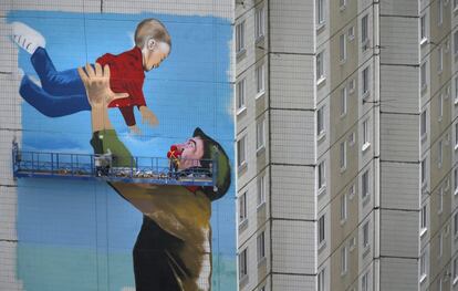 Dos grafiteros pintan un mural en la pared de un edificio en el que se observa a un soldado soviético que juega con un niño en Odintsovo, Moscú (Rusia). Este año se celebra el 70 aniversario de la victoria del Ejército Ruso sobre los nazis.