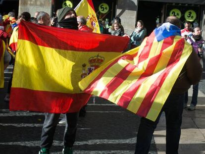 Un ciudadano con una bandera estelada cruza la plaza Sant Jaume junto a otras personas que portan banderas españolas.