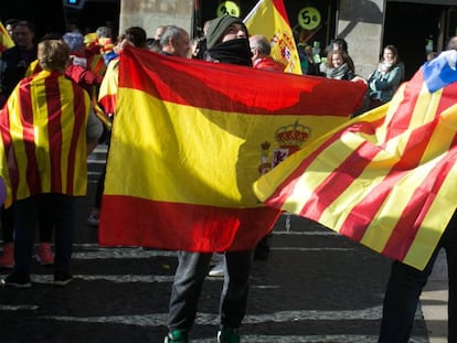 Un ciudadano con una bandera estelada cruza la plaza Sant Jaume junto a otras personas que portan banderas españolas.