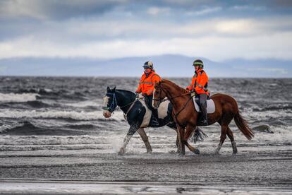 Personal público ejercita sus caballos en la playa de Irvine (Escocia). Muchas áreas de Escocia se verán afectadas por los fuertes vientos y las fuertes lluvias cuando llegue la primera tormenta con nombre -Ali- de la temporada.