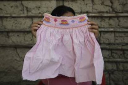 Fotografia que muestra a una mujer trabajando como "bordadora a domicilio" desde su hogar en San Salvador. Al menos 300 mujeres salvadoreñas realizan este oficio desde sus humildes hogares y sin ningún tipo de prestaciones para grandes empresas textiles que exportan sus productos hacia el exterior.