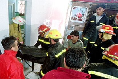 Varios bomberos de Carmen de Patagones retiran uno de los cuerpos de las víctimas de los disparos de un alumno.