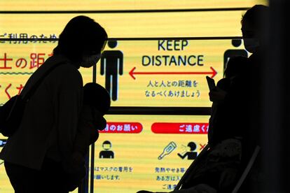 Dos madres con sus bebés en brazos mantienen la distancia social en Tokio (Japón), después de que las autoridades locales anunciaran que se registraron 2.001 nuevos casos de covid-19 en un día.