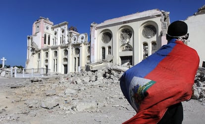 Um homem, coberto pela bandeira haitiana, caminha pelas ruínas da catedral de Porto Príncipe (17/01/2010).