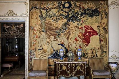 Pared del salón principal decorado en 1945 con cómoda de Herráiz y porcelanas tipo Sèvres junto a tapiz dedicado a Venus y Adonis del siglo XVIII. Puerta hacia el distribuidor en metal, bronce y cristal.