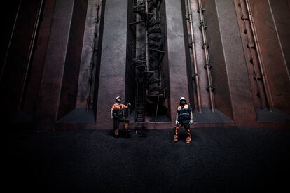 Dos operarios cargan con mineral de hierro la bodega de un buque en Gijón en septiembre de 2020.