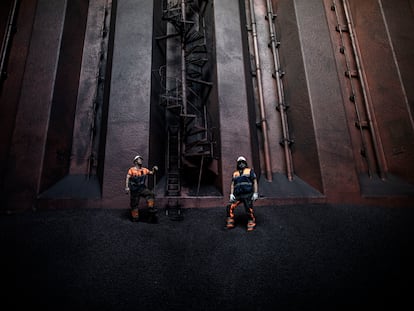 Dos operarios cargan con mineral de hierro la bodega de un buque en Gijón en septiembre de 2020.