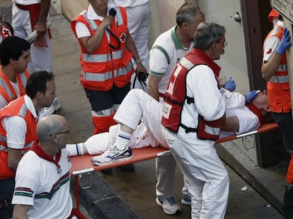 Efectivos de la Cruz Roja trasladan desde la Cuesta de Santo Domingo a un corredor con traumatismo cranoencefálico tras el primer encierro de los Sanfermines.
