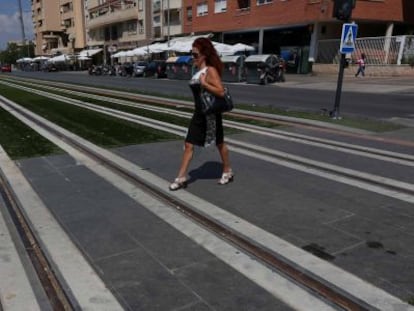 Una mujer cruza por las vías del metro de Granada, en el barrio del Zaidín.