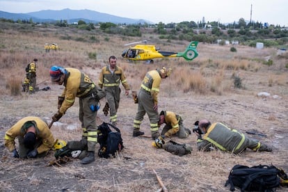 Forest firefighters prepare their equipment before boarding a helicopter to work on extinguishing the wildfire on Monday. 