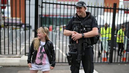 Menina posa com um policial antes do show de Ariana Grande em Manchester, neste domingo.