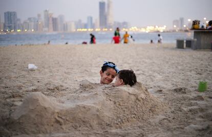 Unos niños juegan entre la arena en la playa de Al Mamzar, Dubái, 25 de octubre 2013.
