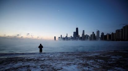 Um homem caminha ao longo da praia da Avenida Norte ao amanhecer de quarta-feira no Lago Michigan, em Chicago (Estados Unidos).