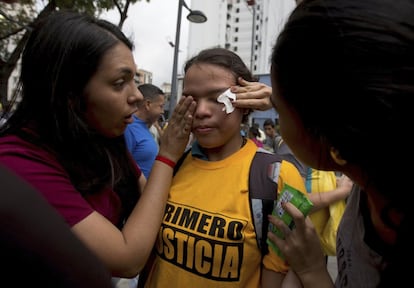 Una manifestante es ayudada tras haber sido atacada con gas pimienta durante una protesta en Caracas.