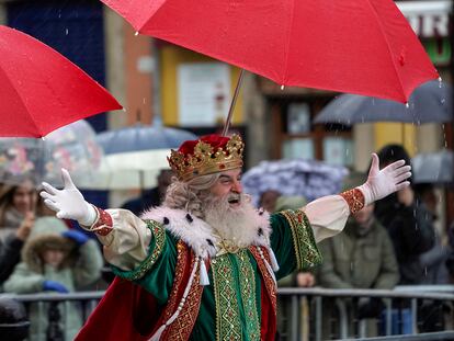 El Rey Melchor protegiéndose de la lluvia la mañana de este viernes en Gijón.