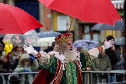 El Rey Melchor protegiéndose de la lluvia la mañana de este viernes en Gijón.