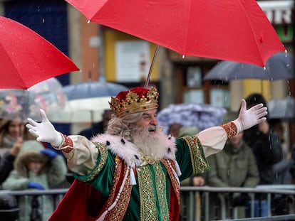 El Rey Melchor protegiéndose de la lluvia la mañana de este viernes en Gijón.