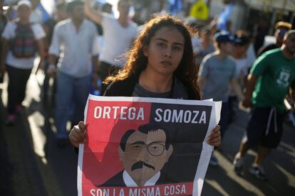 Una joven sujeta un cartel del presidente de Nicaragua, Daniel Ortega comparándolo con el expresidente Anastasio Somoza durante la protesta en Managua (Nicaragua).