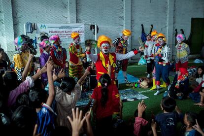 Un payaso entretiene a niños desplazados por el tsunami en un centro de evacuación en Labuan (Indonesia).