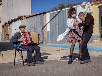 Sandra García, la directora de la residencia de mayores de Pescueza (Cáceres), baila con Gabino Sánchez, uno de los residentes, mientras otro de ellos, Isidoro Martín, toca el acordeón.