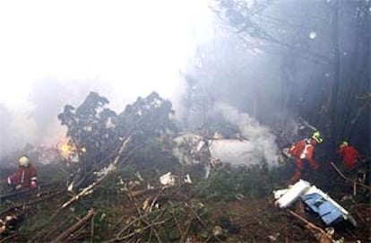Los bomberos intentan apagar el fuego entre los restos del avión.
