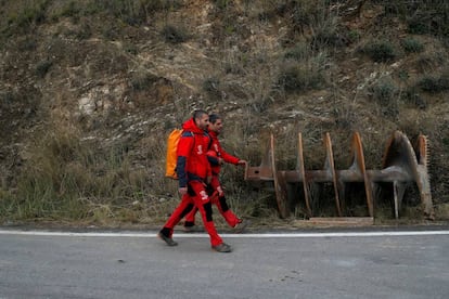 Mountain rescue firefighters walk past a drill bit after leaving the area.