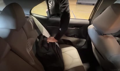 A car thief taking a backpack from the back seat of a vehicle.