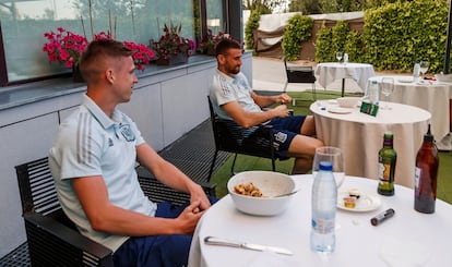 Dani Olmo y Unai Simón siguen a través de un teléfono móvil el amistoso entre España, que juega con el equipo sub 21, y Lituania, este martes en la Ciudad del Fútbol de Las Rozas, en Madrid.