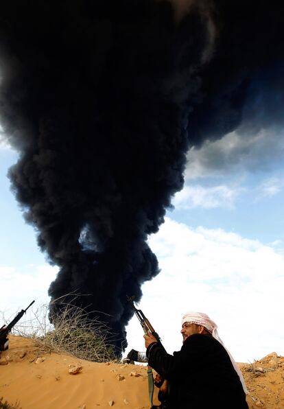 Un rebelde observa una columna de humo tras un bombardeo de las fuerzas leales a Gadafi.