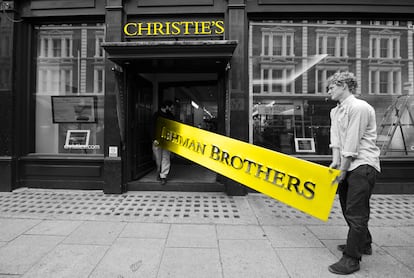 Empleados de la casa de subastas Christie's con el cartel principal de la empresa de inversiones Lehman Brothers, que quebró en 2008.