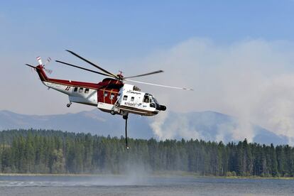 Un helicóptero contraincendios carga su depósito de agua en el lago Seeley, Montana (EE UU).
