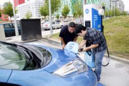 Un operario coloca junto al cliente el enchufe en el coche. EFE/Archivo