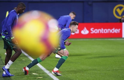 Los jugadores del Betis entran en calor con la valla publicitaria de Banco Santander de fondo.