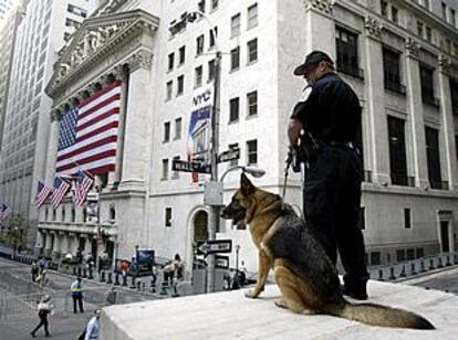 Un policía y un perro adiestrado vigilan la entrada del edificio de la Bolsa de Nueva York, en Wall Street. PLANO GENERAL - PAISAJE URBANO