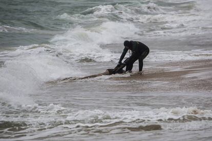 Un agente de la Guardia Civil rescata el cadáver de un inmigrante el pasado jueves en una playa de Caños de Meca en Cádiz.