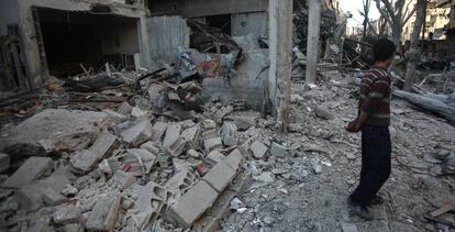 Un chico camina junto a las ruinas de un edificio, en Douma (Siria).