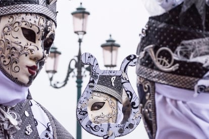 Una pareja vestidos con mascaras en la plaza de San Marcos en Venecia (Italia).