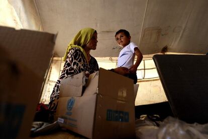 Una madre siria, desplazada de sus hogar en Deir Ezzor, viste a su hijo con ropa recibida como parte de la ayuda humanitaria proporcionada por el Fondo de las Naciones Unidas para la Infancia (UNICEF) en su campamento de la ciudad siria oriental de Hasakeh, el pasado 16 de agosto. La ONU estima que 136 millones de personas necesitarán asistencia urgente durante 2018.