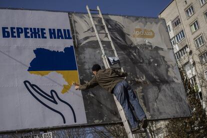 Un trabajador coloca una valla publicitaria con los colores de la bandera de Ucrania en Novoiavorisk, cerca de Lviv, el viernes. El primer ministro polaco, Mateusz Morawiecki, ha pedido una ruptura total de las relaciones comerciales entre la UE y Rusia, una idea que está lejos de ser compartida por todos los socios comunitarios, como se teme Bruselas.