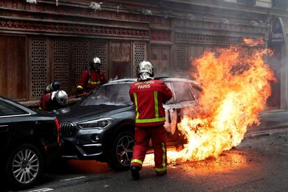 El ministro del Interior, Christophe Castaner, denunció actos de "profesionales del destrozo y del desorden" y pidió a la policía responder con "la mayor firmeza a estos ataques inadmisibles". En la imagen, los bomberos sofocan las llamas de un coche incendiado durante los disturbios en París (Francia), este sábado.