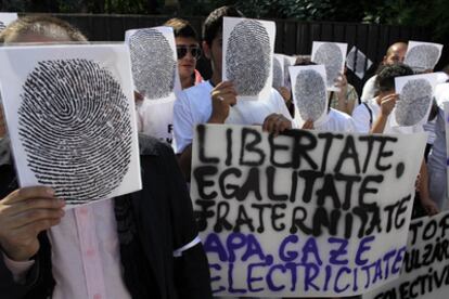 Miembros de la Alianza Cívica para los Roma se tapan las caras con pancartas con huellas dactilares durante la manifestación frente a la embajada francesa de Bucarest.