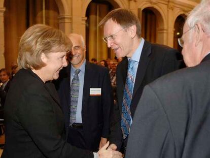 Angela Merkel y Janez Potocnik se saludan en presencia de Fotis Kafatos en Berlín.