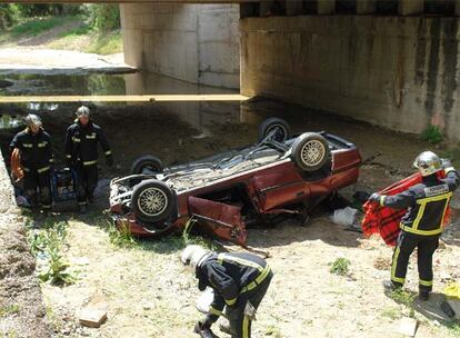 Cuatro bomberos, junto al coche que ayer se desplomó desde un puente de la M-501.