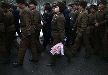 Una miembro del ejército norcoreano sostiene un ramo de flores de camino a las estatuas de bronce de los líderes norcoreanos en el Gran Monumento Mansu Hill, en Pyongyang.