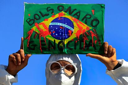 Manifestante levanta bandeira do Brasil com a inscrição "Bolsonaro genocida" em protesto em Brasília, na quarta.