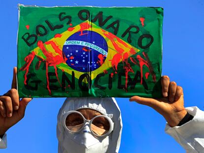 Manifestante levanta bandeira do Brasil com a inscrição "Bolsonaro genocida" em protesto em Brasília, na quarta.