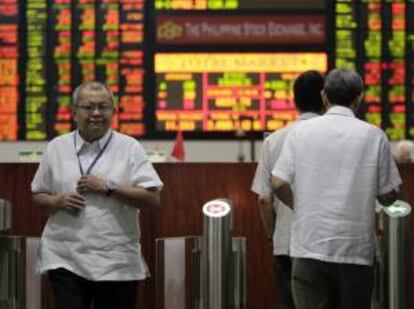 Corredores de bolsa filipinos atraviesan la entrada de la sede de la Bolsa de Filipinas (PSE) en la ciudad de Makati, al sur de Manila, en Filipinas. EFE/Archivo