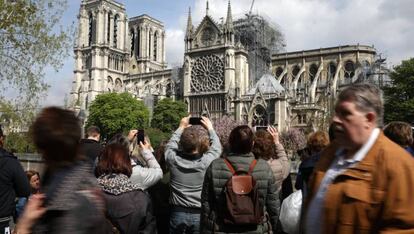 Varios transeúntes sacan fotos de Notre Dame, el miércoles 17 de abril. 