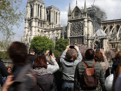 Varios transeúntes sacan fotos de Notre Dame, el miércoles 17 de abril.